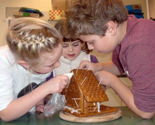 Schüler bauen gemeinsam ein Lebkuchenhaus in der Nachmittagsbetreuung.